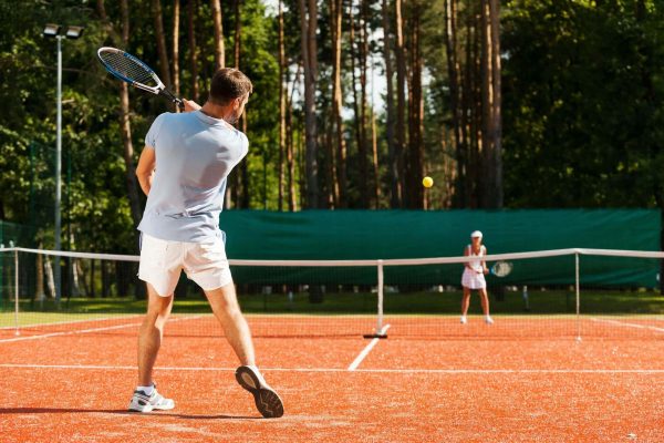 Match point. Full length of man and woman playing tennis on tennis court